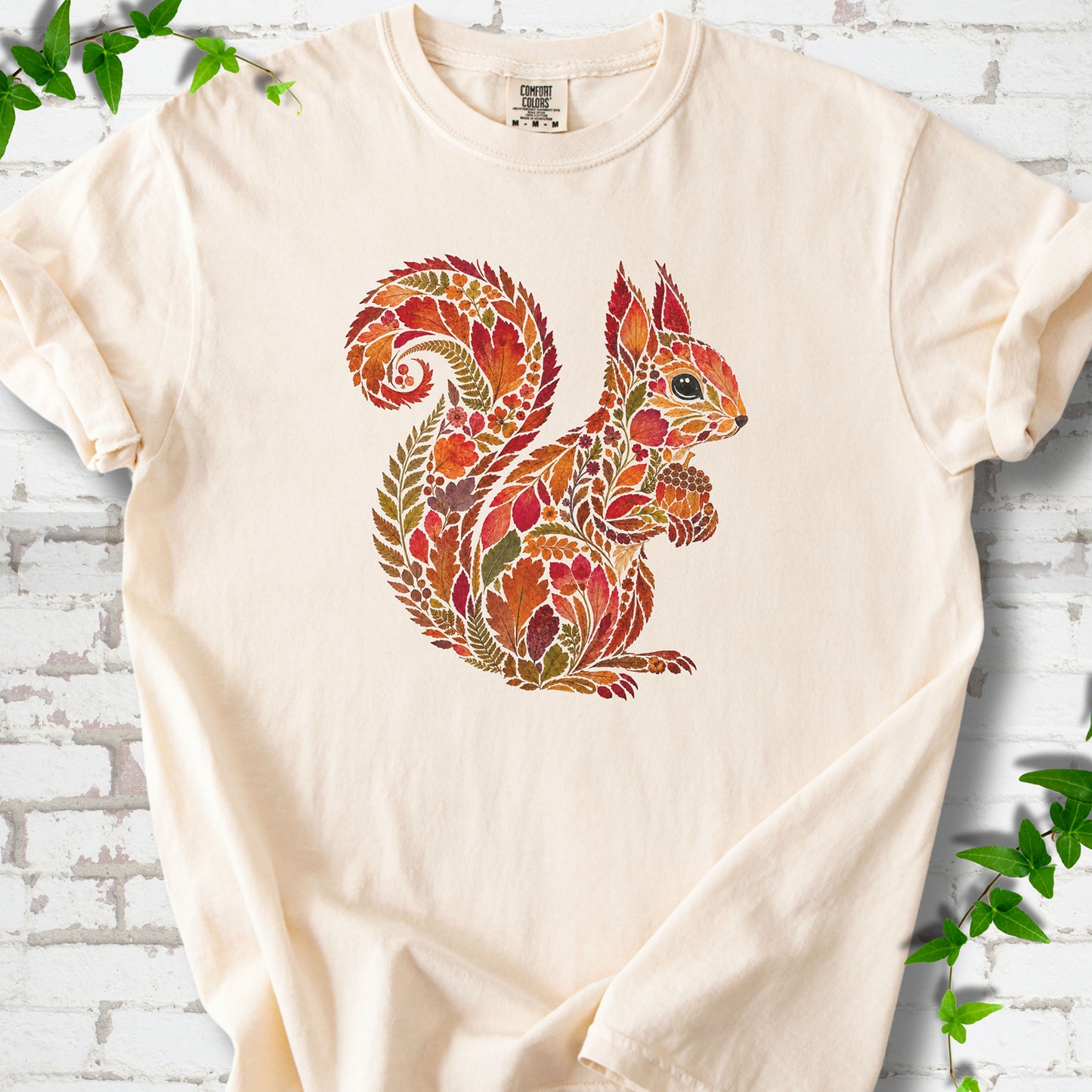 Yam Comfort Colors® T-shirt flat lay with an autumn squirrel graphic made from colorful leaves, ferns and flowers.