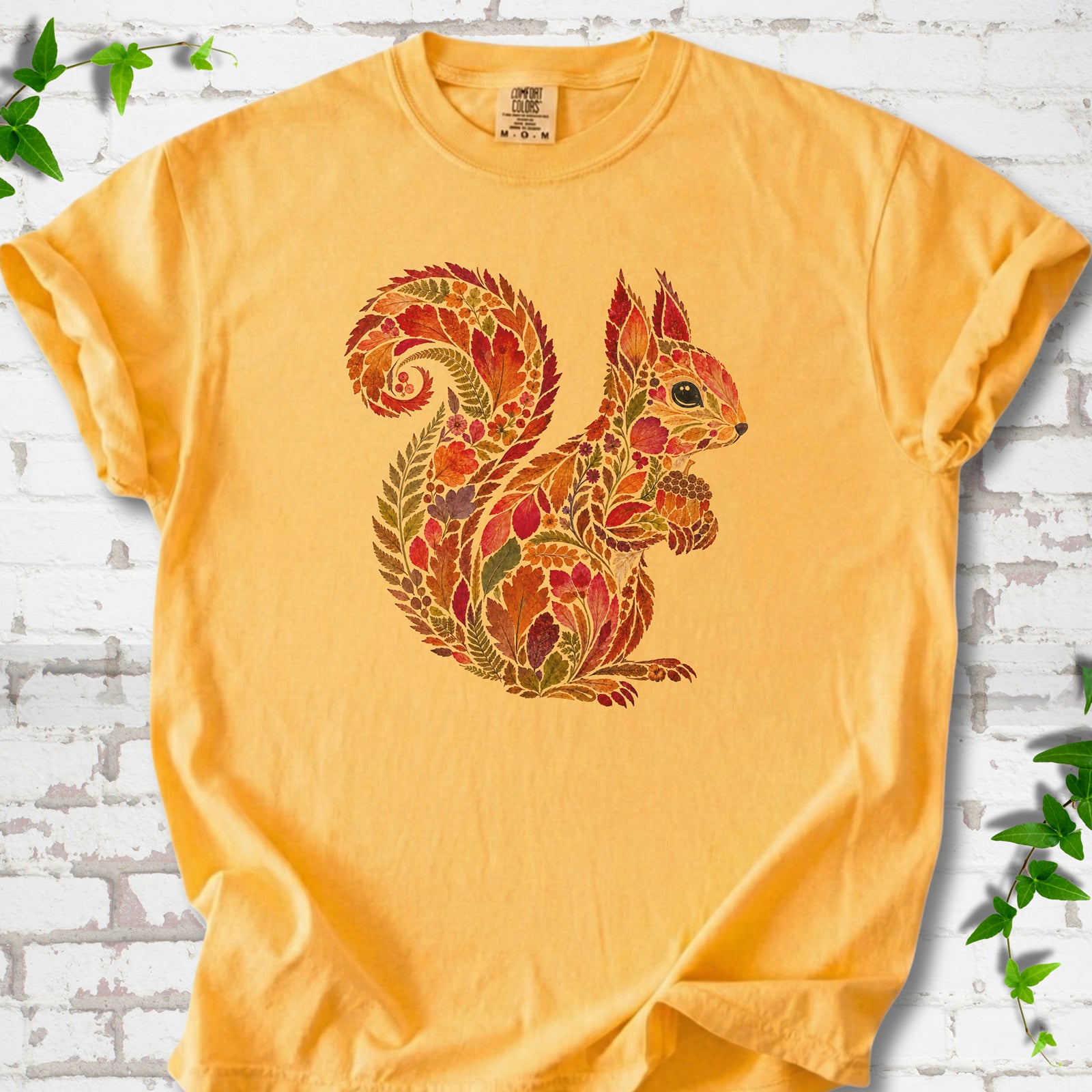 Bay Comfort Colors® T-shirt flat lay with an autumn squirrel graphic made from colorful leaves, ferns and flowers.