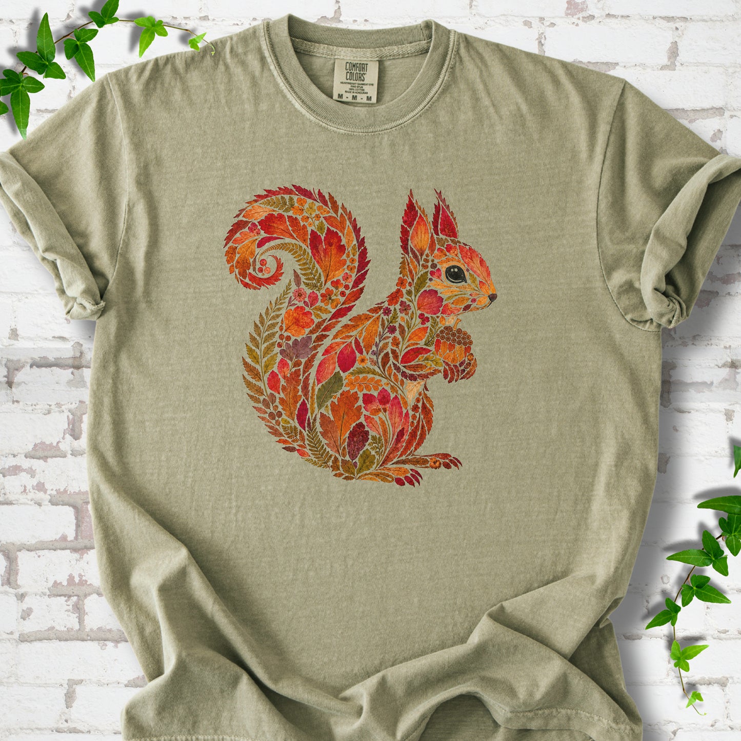 Citrus Comfort Colors® T-shirt flat lay with an autumn squirrel graphic made from colorful leaves, ferns and flowers.