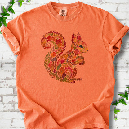 Burnt Orange Comfort Colors® T-shirt flat lay with an autumn squirrel graphic made from colorful leaves, ferns and flowers.