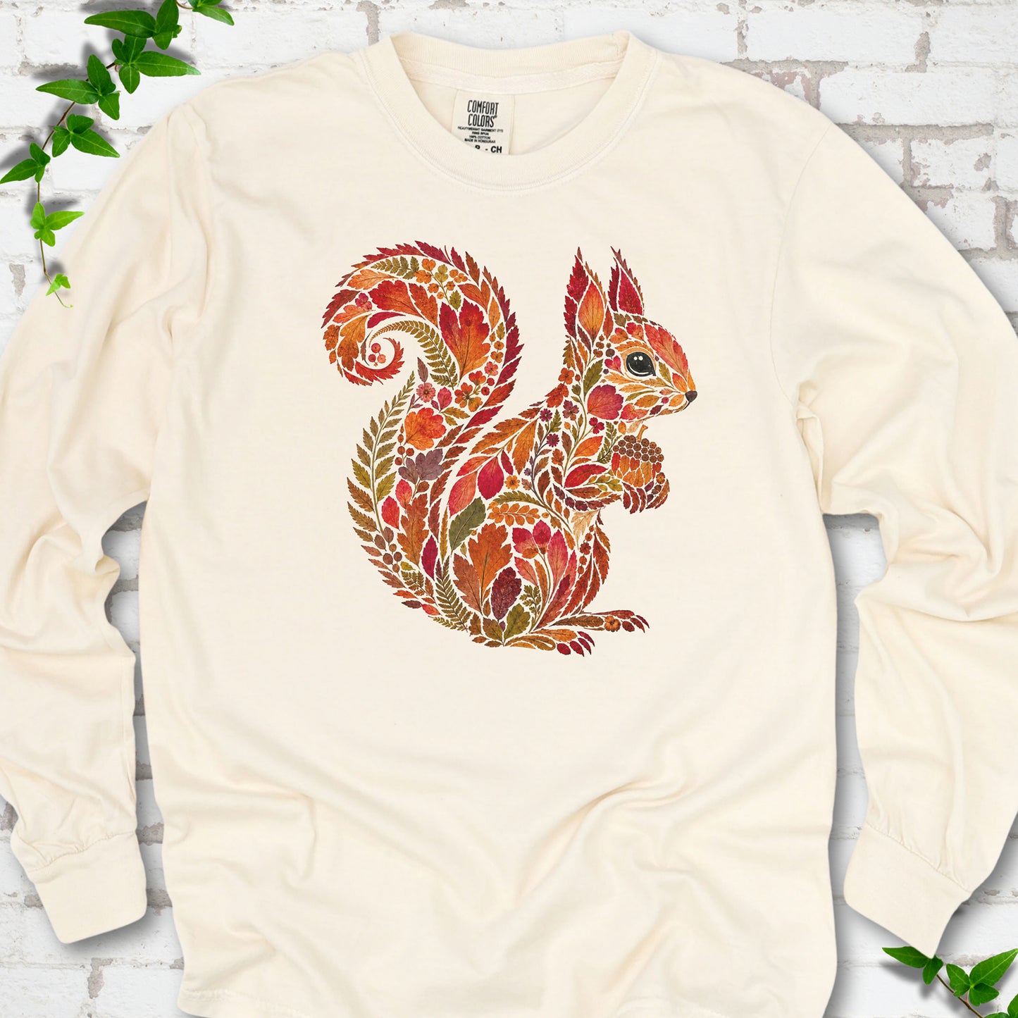 Espresso Comfort Colors® long sleeve T-shirt flat lay with an autumn squirrel graphic made from colorful leaves, ferns and flowers.
