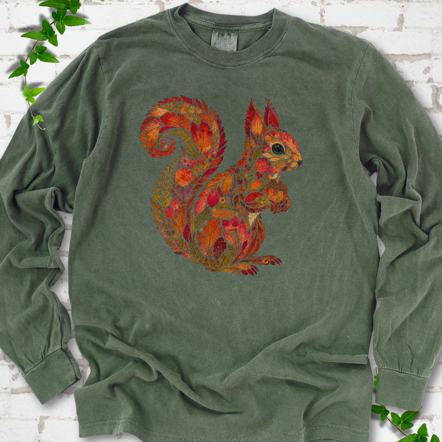 Ivory Comfort Colors® long sleeve T-shirt flat lay with an autumn squirrel graphic made from colorful leaves, ferns and flowers.