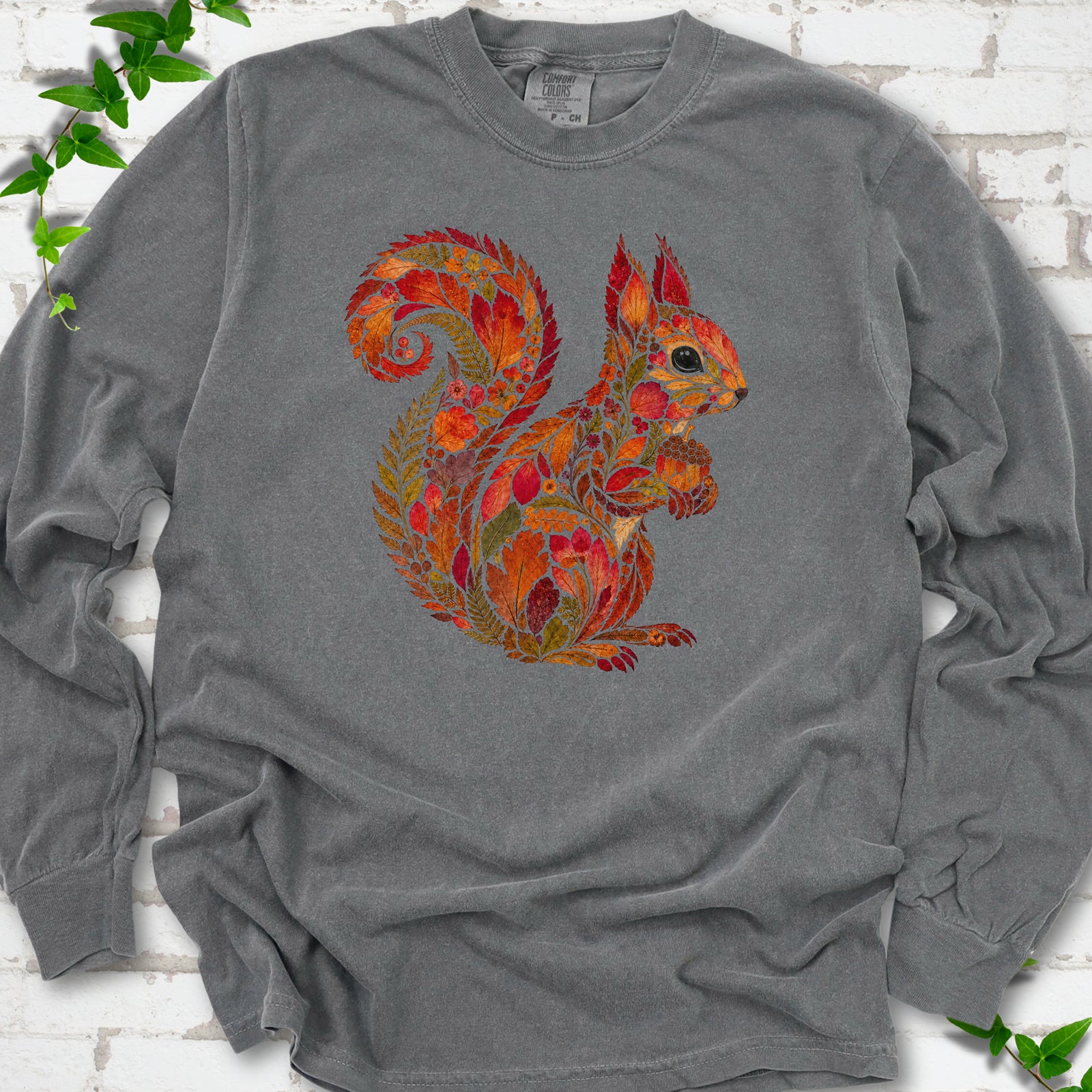 Butter Comfort Colors® long sleeve T-shirt flat lay with an autumn squirrel graphic made from colorful leaves, ferns and flowers.