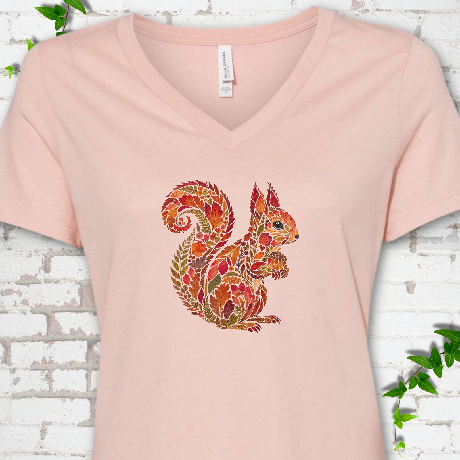 Heather Olive Bella Canvas® V-neck T-shirt flat lay with an autumn squirrel graphic made from colorful leaves, ferns and flowers.