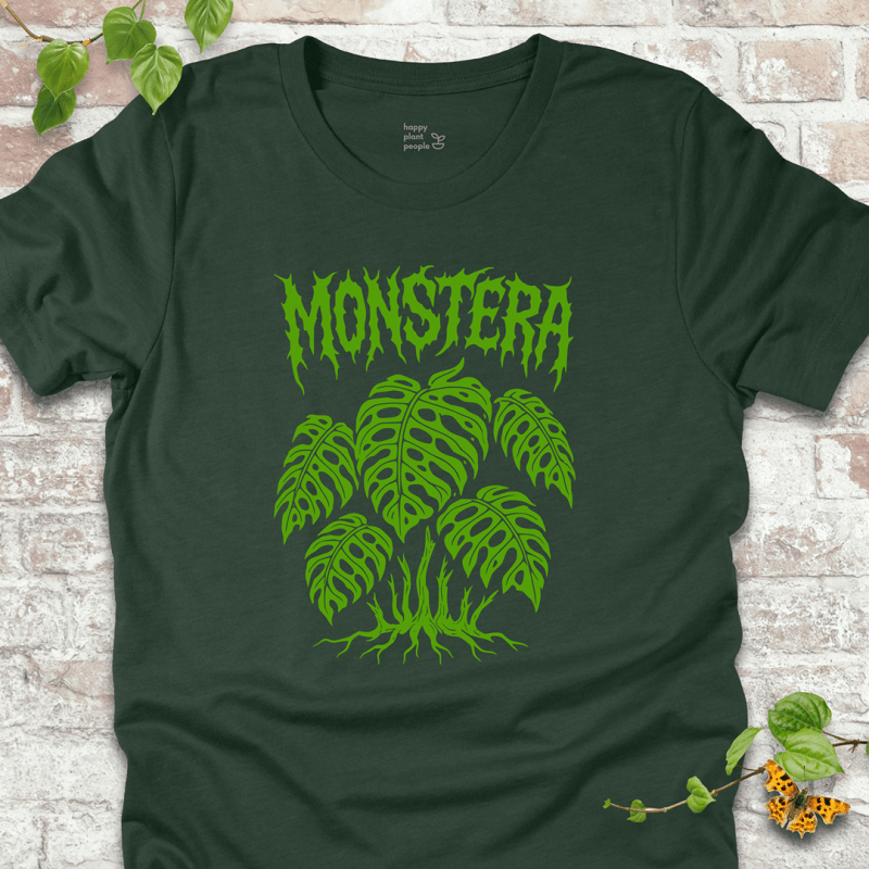 Bold Monstera gothic plant T-shirt in heather forest green, displayed on a rustic background