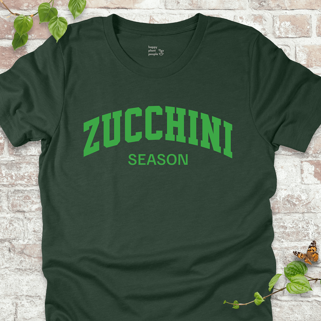 Zucchini Season T-Shirt in Heather Forest, featuring bold varsity-style cream text on soft Bella+Canvas tee.