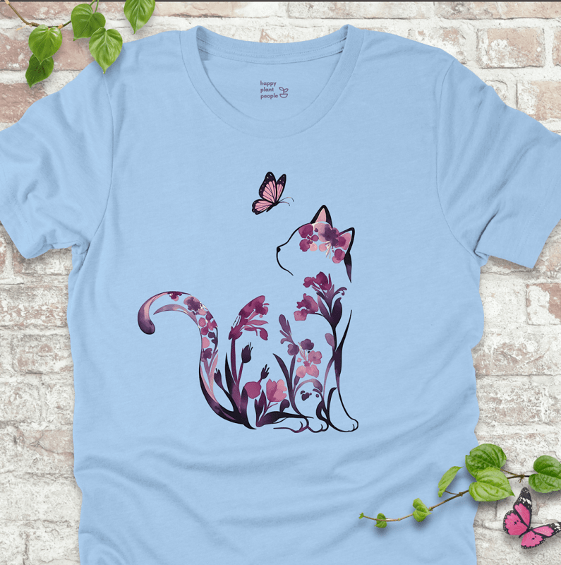 Ladies T-shirt in light blue with a floral cat illustration. Whimsical garden-themed shirt for cat lovers and flower fans.