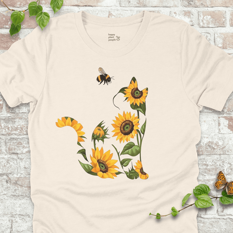 Cute T-shirt in natural with a floral cat design made of sunflowers and a bee. Cozy fall garden-themed shirt for plant lovers and cat fans.