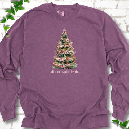 Berry long sleeve T-shirt laid flat, featuring a decorated evergreen tree with pink ribbon garlands, a pink bow and gold ornaments above the words 'All is calm, all is bright.'