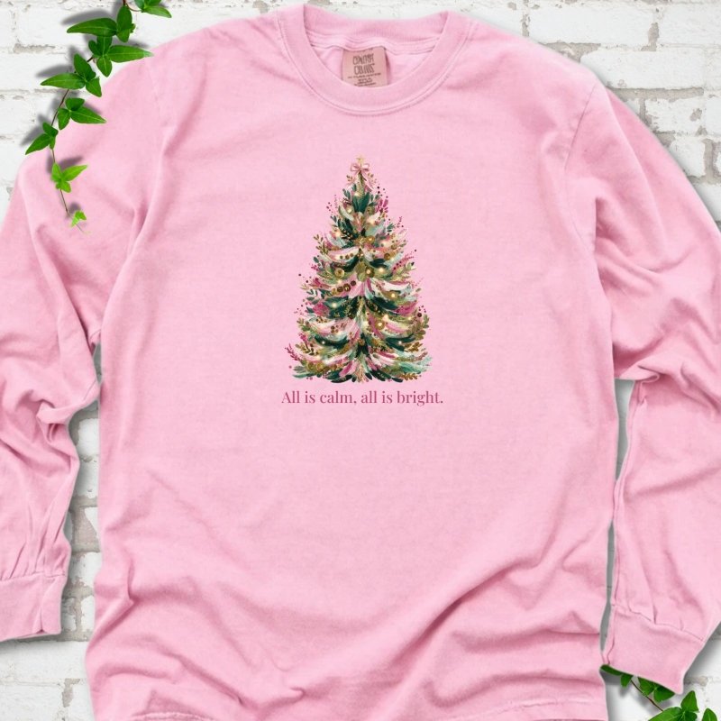 Blossom long sleeve T-shirt laid flat, featuring a decorated evergreen tree with pink ribbon garlands, a pink bow and gold ornaments above the words 'All is calm, all is bright.'