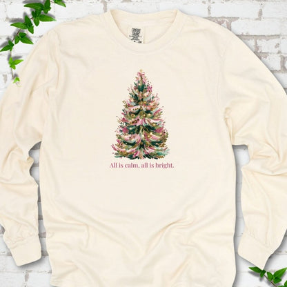 Ivory long sleeve T-shirt laid flat, featuring a decorated evergreen tree with pink ribbon garlands, a pink bow and gold ornaments above the words 'All is calm, all is bright.'