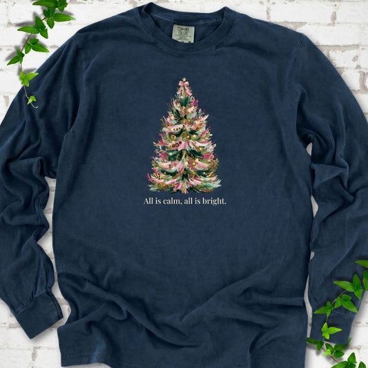 Midnight long sleeve T-shirt laid flat, featuring a decorated evergreen tree with pink ribbon garlands, a pink bow and gold ornaments above the words 'All is calm, all is bright.'