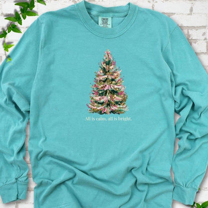 Seafoam long sleeve T-shirt laid flat, featuring a decorated evergreen tree with pink ribbon garlands, a pink bow and gold ornaments above the words 'All is calm, all is bright.'
