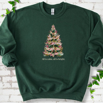 Forest Green sweatshirt laid flat, featuring a decorated evergreen tree with pink ribbon garlands, a pink bow and gold ornaments above the words 'All is calm, all is bright.'
