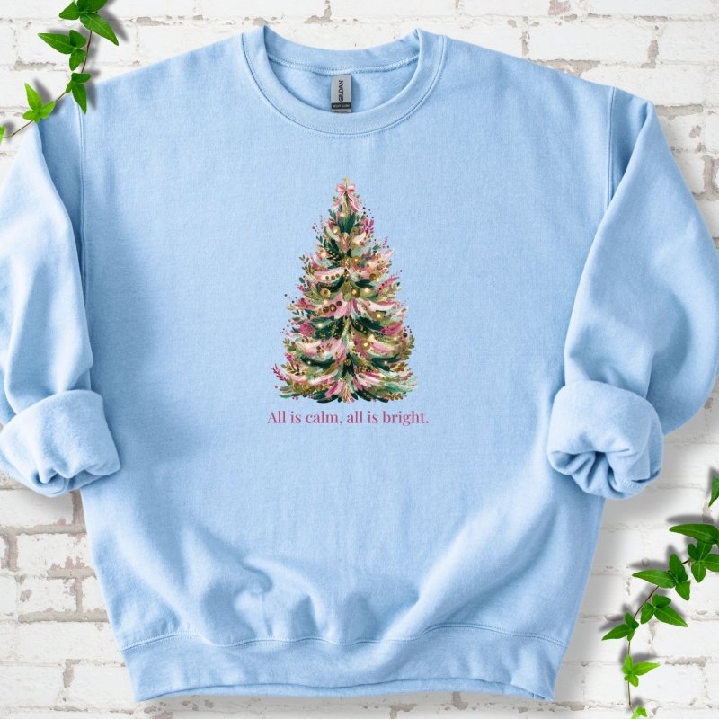 Light Blue sweatshirt laid flat, featuring a decorated evergreen tree with pink ribbon garlands, a pink bow and gold ornaments above the words 'All is calm, all is bright.'