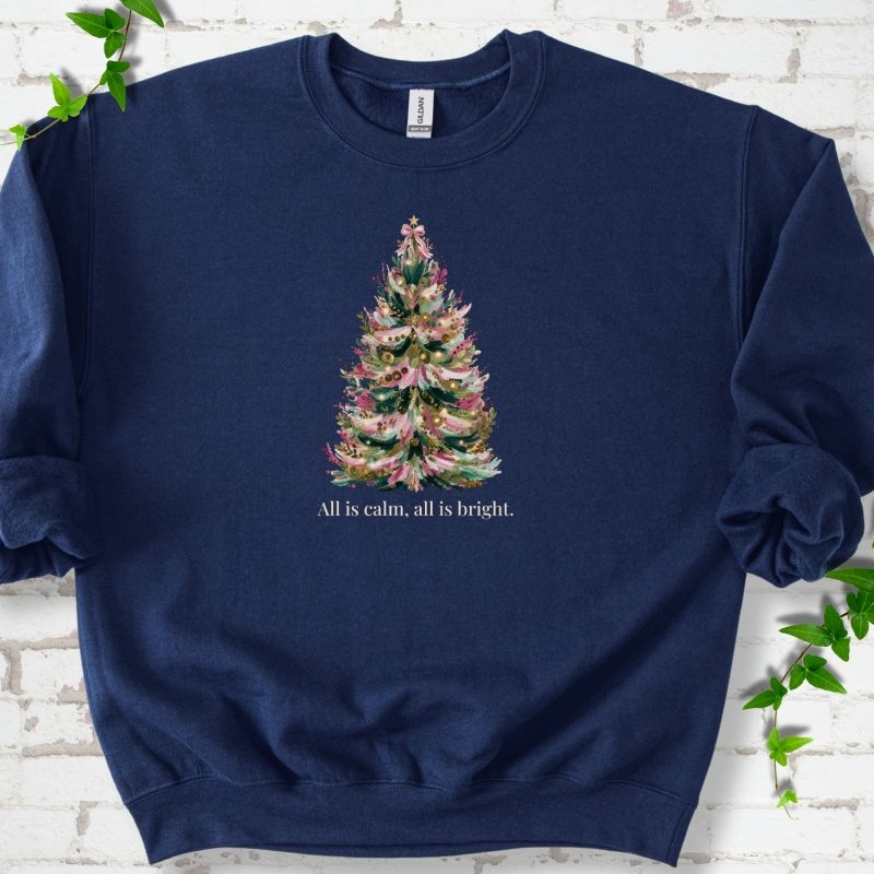 Navy sweatshirt laid flat, featuring a decorated evergreen tree with pink ribbon garlands, a pink bow and gold ornaments above the words 'All is calm, all is bright.'