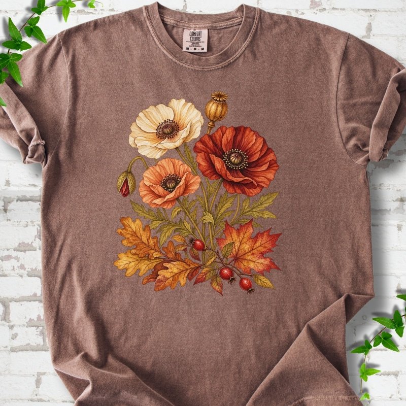 Espresso brown short sleeve t-shirt with a botanical bouquet of cream, peach and deep red poppies with a seed pod, oak and maple leaves and red rose hips, printed on the chest, flat lay on white brick with ivy