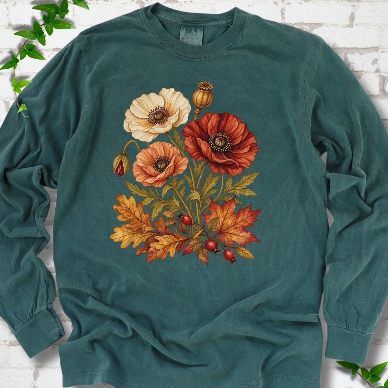 Blue Spruce deep teal long sleeve t-shirt with a botanical bouquet of cream, peach and deep red poppies with a seed pod, oak and maple leaves and red rose hips, printed on the chest, flat lay on white brick with ivy