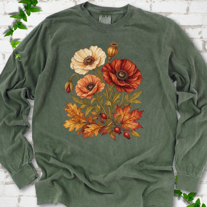 Hemp dark green long sleeve t-shirt with a botanical bouquet of cream, peach and deep red poppies with a seed pod, oak and maple leaves and red rose hips, printed on the chest, flat lay on white brick with ivy