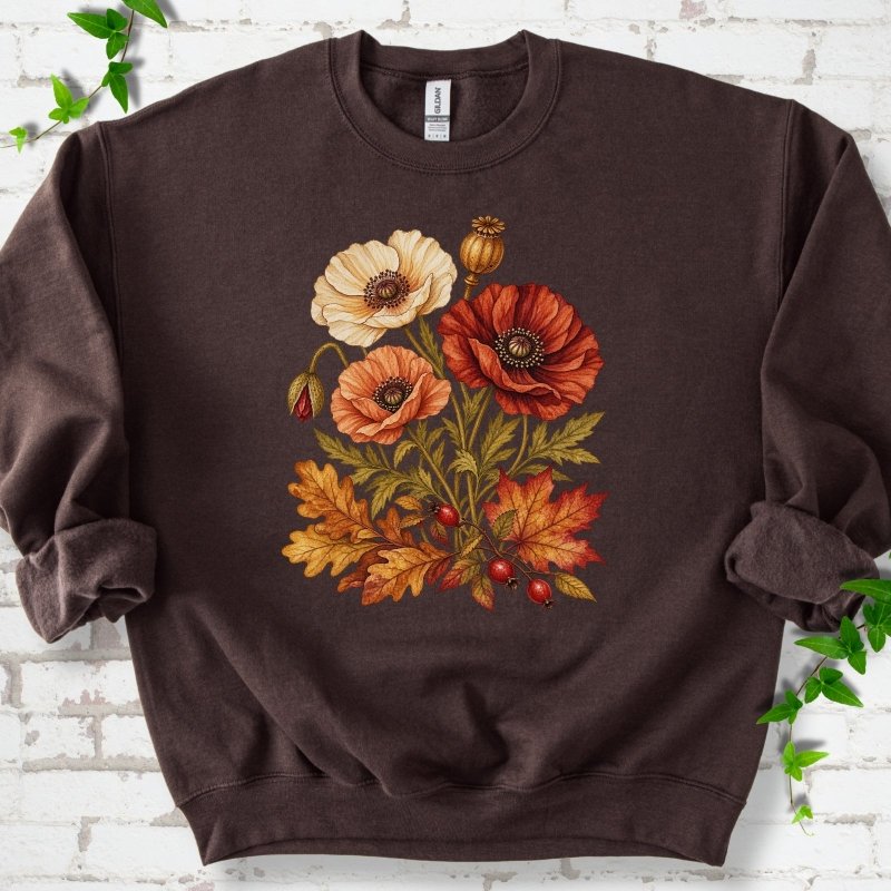Dark Chocolate brown crewneck sweatshirt with a botanical bouquet of cream, peach and deep red poppies with a seed pod, oak and maple leaves and red rose hips, printed on the chest, flat lay on white brick with ivy