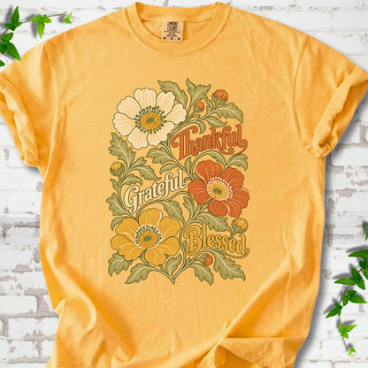 Citrus T-shirt flat-lay mockup with orange, cream and yellow flowers framing "Thankful, Grateful, Blessed" lettering.