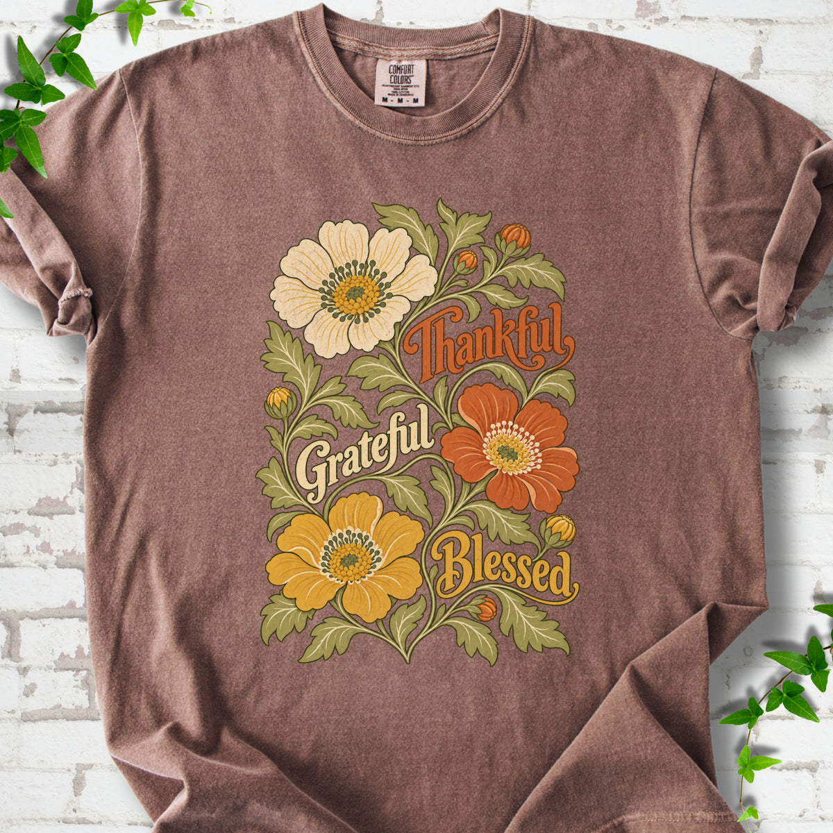 Espresso T-shirt flat-lay mockup with orange, cream and yellow flowers framing "Thankful, Grateful, Blessed" lettering.
