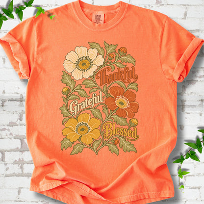 Melon T-shirt flat-lay mockup with orange, cream and yellow flowers framing "Thankful, Grateful, Blessed" lettering.