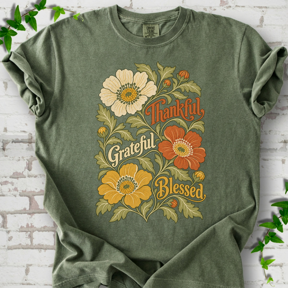 Moss T-shirt flat-lay mockup with orange, cream and yellow flowers framing "Thankful, Grateful, Blessed" lettering.