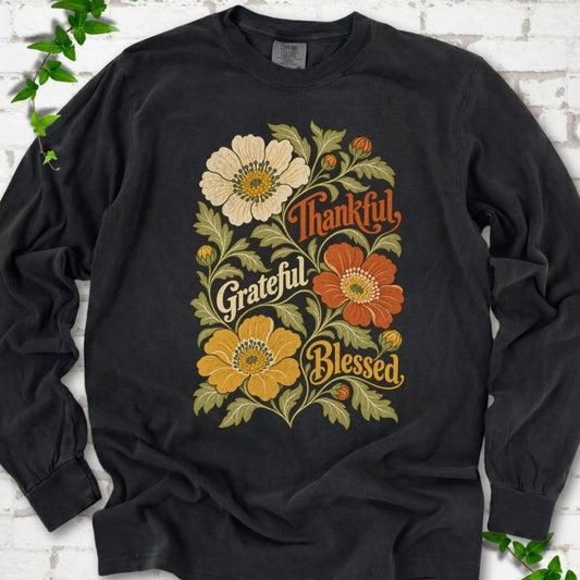 Black long sleeve T-shirt flat-lay mockup with orange, cream and yellow flowers framing "Thankful, Grateful, Blessed" lettering.