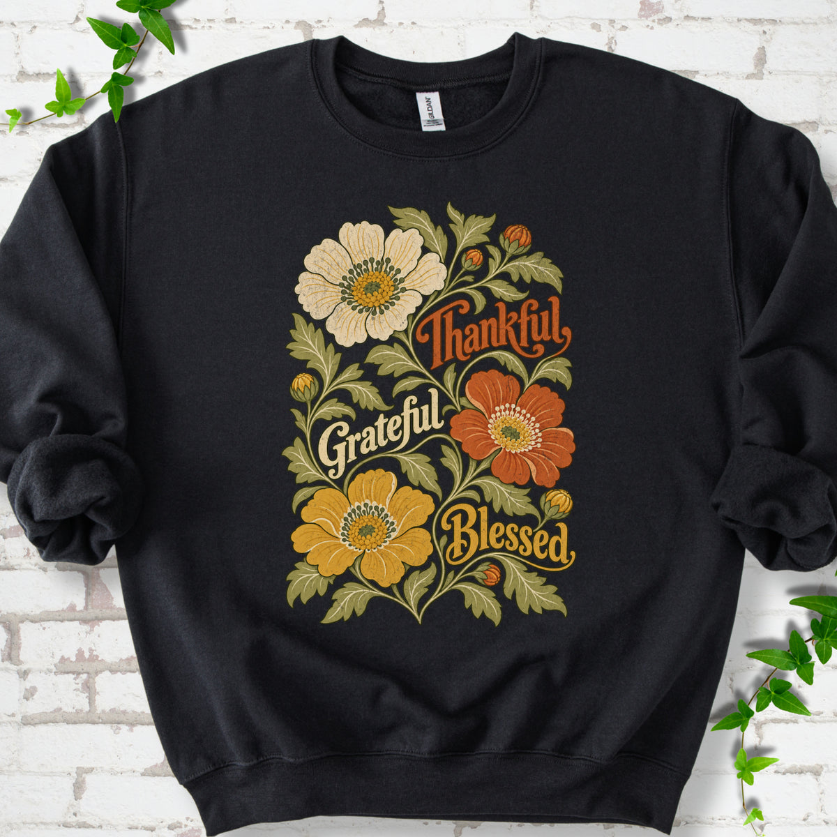 Black sweatshirt flat-lay mockup with orange, cream and yellow flowers framing "Thankful, Grateful, Blessed" lettering.