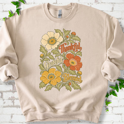 Sand sweatshirt flat-lay mockup with orange, cream and yellow flowers framing "Thankful, Grateful, Blessed" lettering.