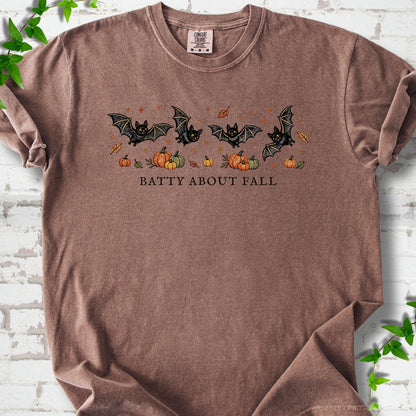 Espresso Comfort Colors® T-shirt flat lay featuring four black bats above pumpkins and autumn leaves with “Batty About Fall” lettering.