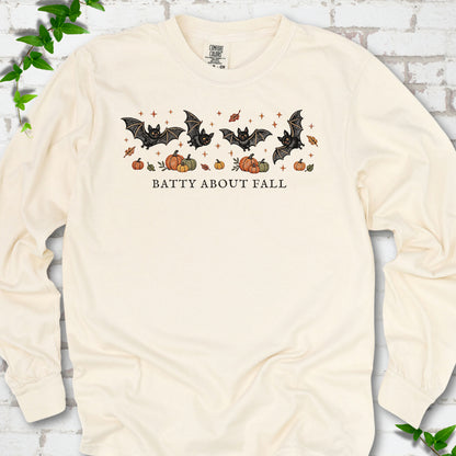 Ivory Comfort Colors® long sleeve tee flat lay featuring four black bats above pumpkins and autumn leaves with “Batty About Fall” lettering.