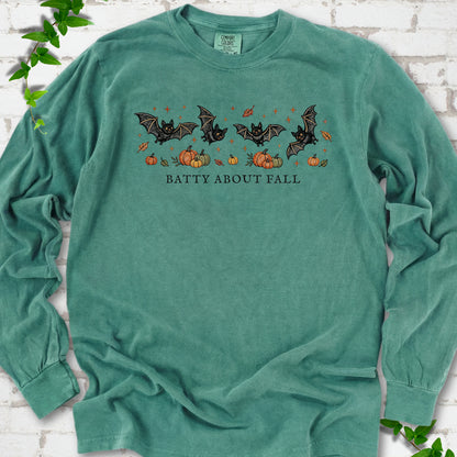 Light Green Comfort Colors® long sleeve tee flat lay featuring four black bats above pumpkins and autumn leaves with “Batty About Fall” lettering.