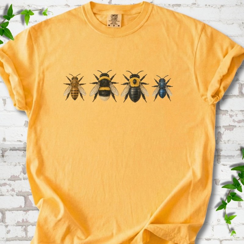 Citrus yellow short sleeve t-shirt with a row of four bees across the chest: a slim golden honey bee, a fuzzy black and yellow bumble bee, a glossy black bee with a yellow collar and a small metallic blue bee, flat lay on white brick with ivy