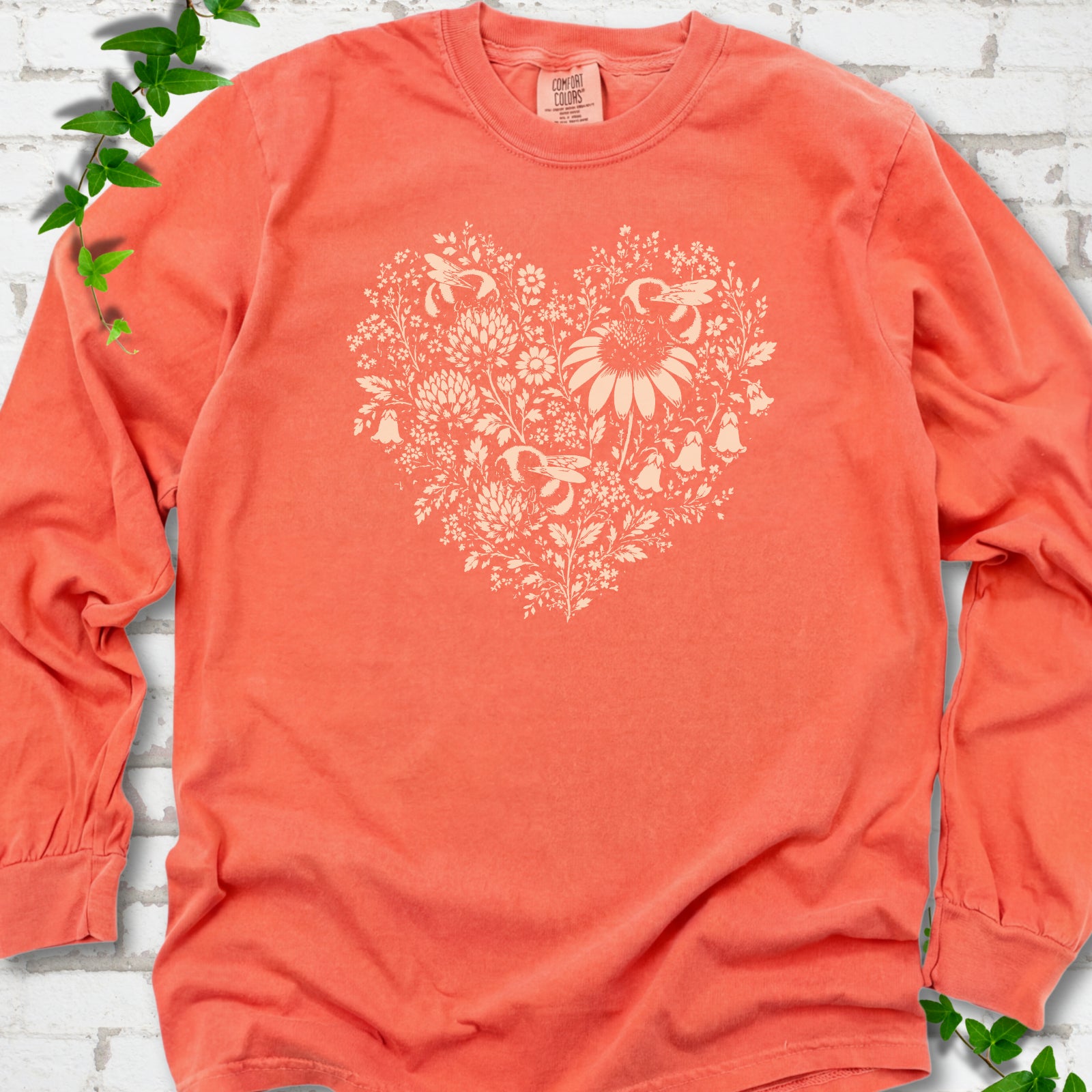Bright Salmon Comfort Colors® long sleeve T-shirt front mockup featuring three bumblebees among wildflowers in a heart-shaped design.