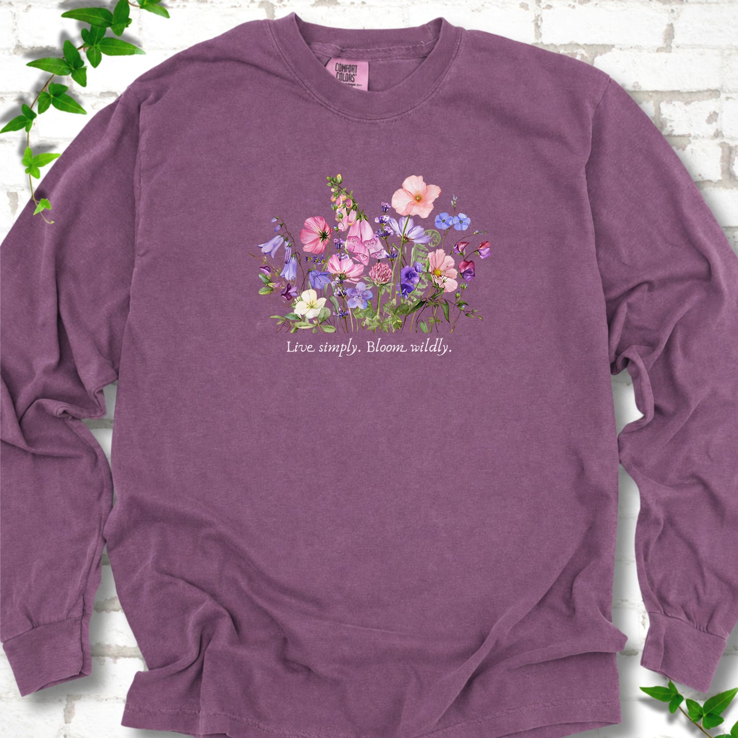 Berry Comfort Colors® long sleeve T-shirt front mockup featuring colorful wildflowers and the words “Live simply. Bloom wildly.”