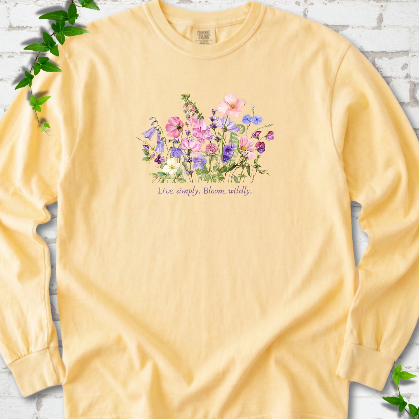 Butter Comfort Colors® long sleeve T-shirt front mockup featuring colorful wildflowers and the words “Live simply. Bloom wildly.”