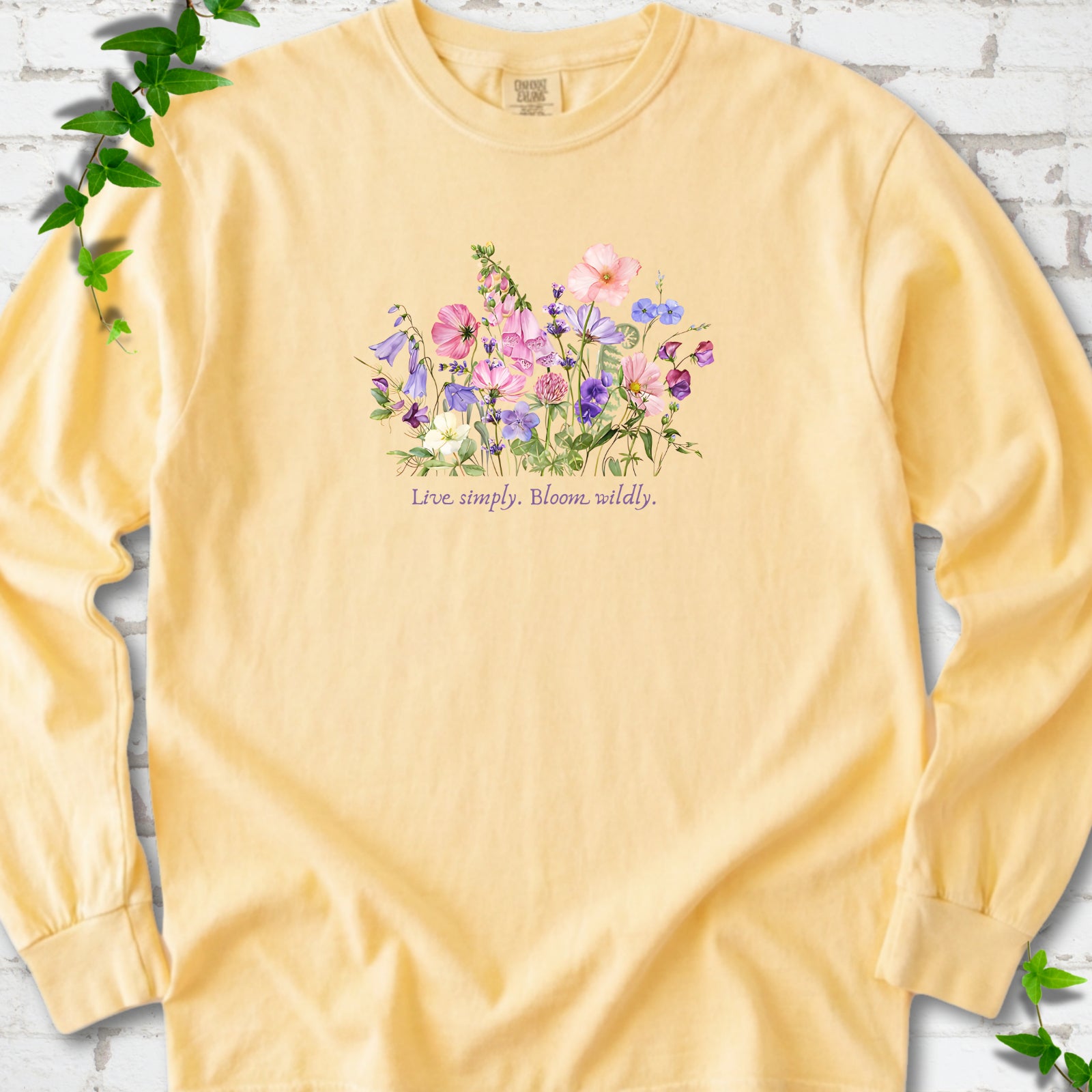 Butter Comfort Colors® long sleeve T-shirt front mockup featuring colorful wildflowers and the words “Live simply. Bloom wildly.”
