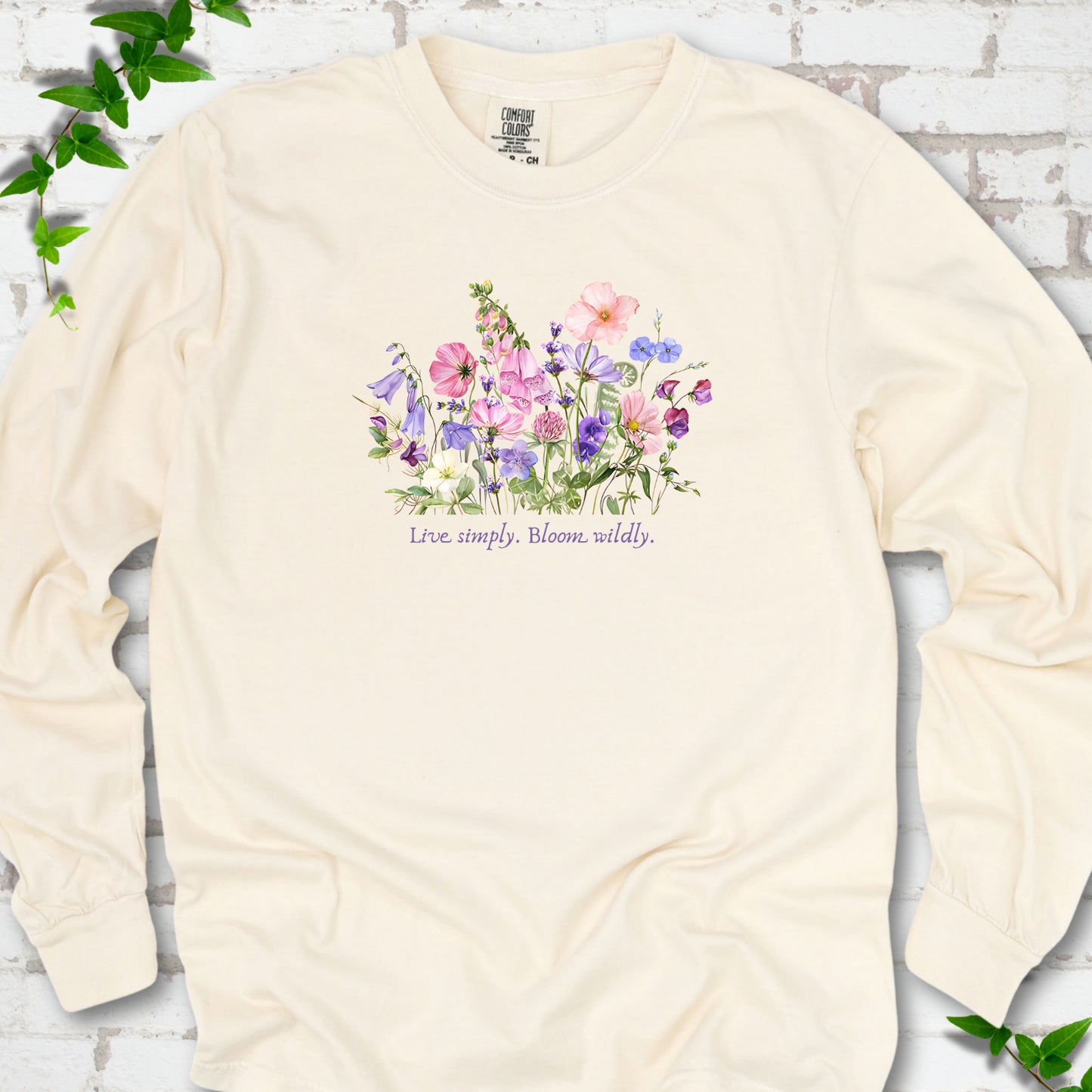 Ivory Comfort Colors® long sleeve T-shirt front mockup featuring colorful wildflowers and the words “Live simply. Bloom wildly.”