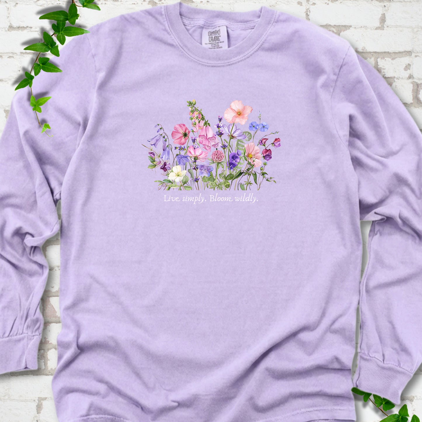 Orchid Comfort Colors® long sleeve T-shirt front mockup featuring colorful wildflowers and the words “Live simply. Bloom wildly.”
