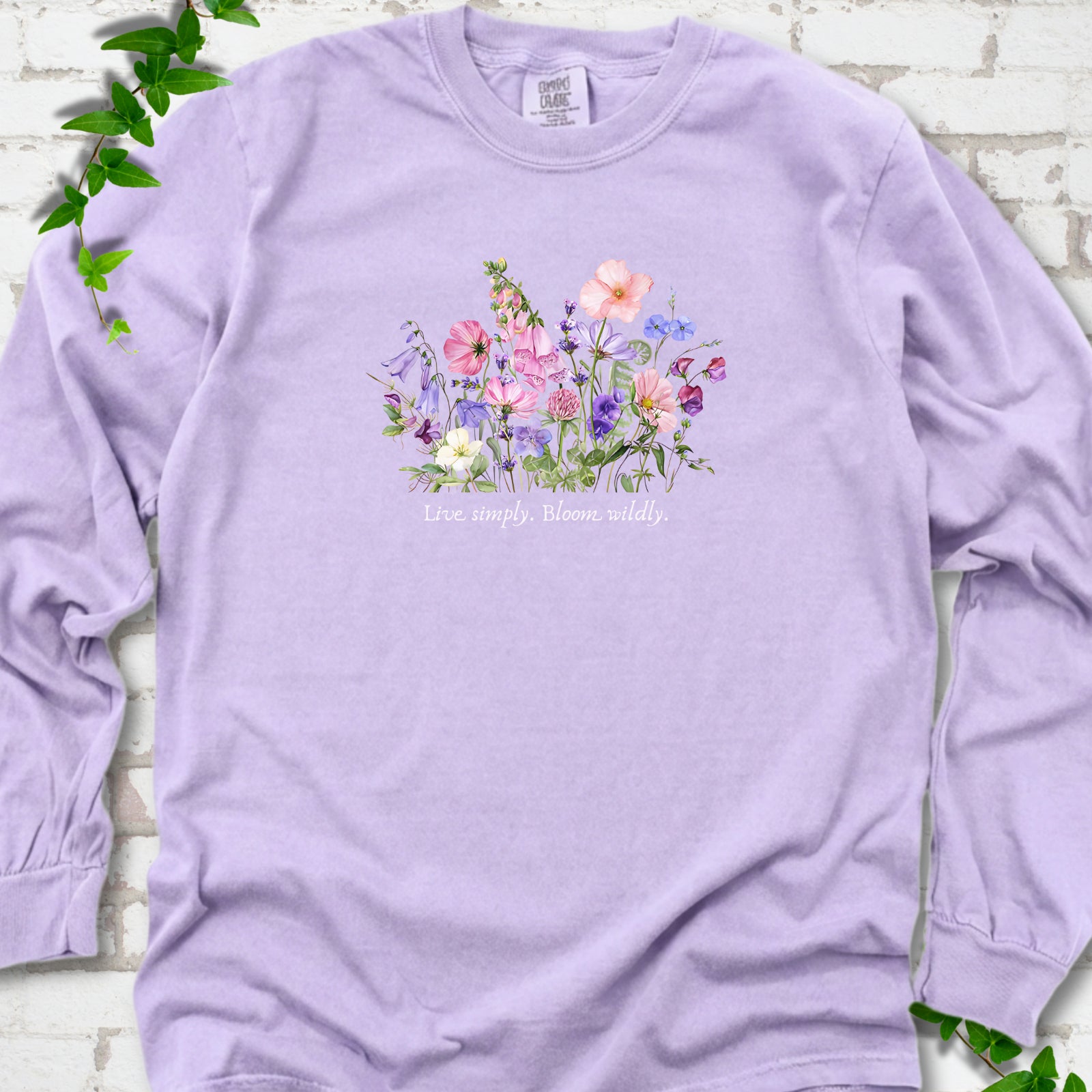 Orchid Comfort Colors® long sleeve T-shirt front mockup featuring colorful wildflowers and the words “Live simply. Bloom wildly.”
