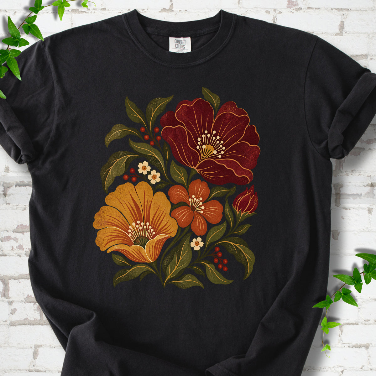 Black T-shirt front-view mockup with a large burgundy, ochre and rust retro floral graphic.
