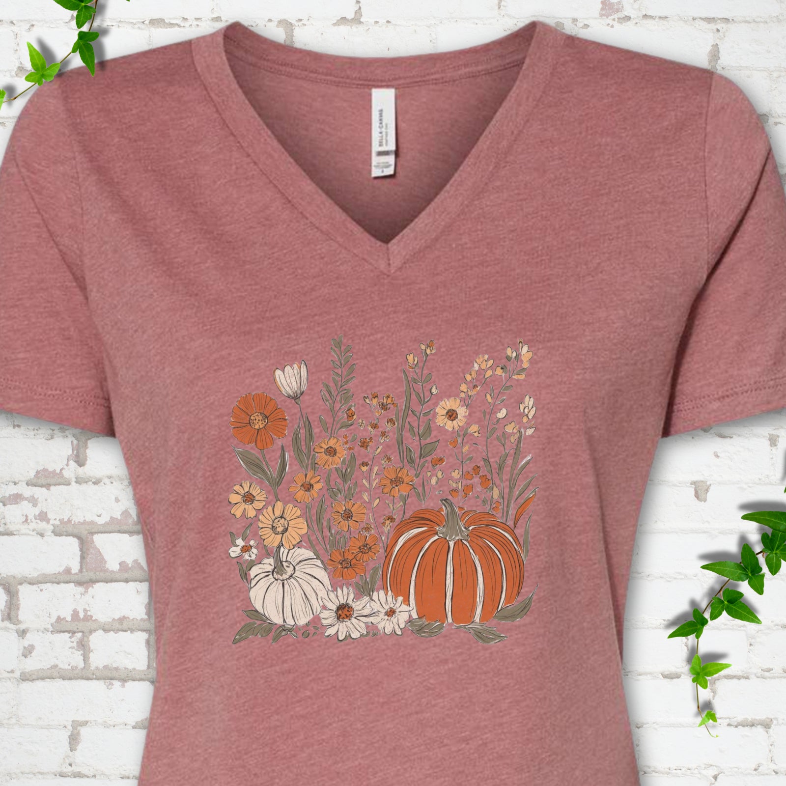 Heather Mauve Bella Canvas® V-neck T-shirt flat lay featuring an orange pumpkin surrounded by cream and orange wildflowers.