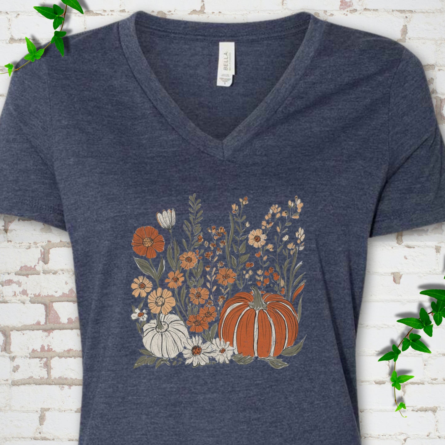 Heather Navy Bella Canvas® V-neck T-shirt flat lay featuring an orange pumpkin surrounded by cream and orange wildflowers.