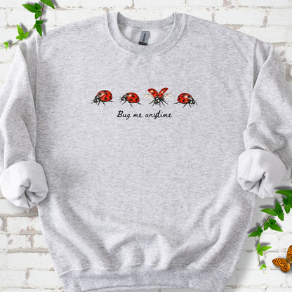 Ash classic sweatshirt laid flat, showing four red and black ladybugs above "Bug me anytime" lettering.