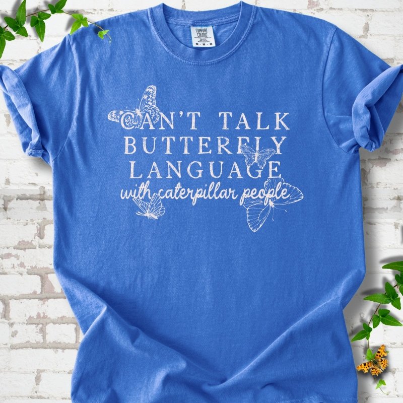 Flo Blue Comfort Colors® T-shirt featuring a cream Can't Talk Butterfly Language with Caterpillar People graphic with butterflies