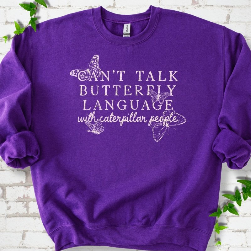 Purple classic sweatshirt featuring a cream Can't Talk Butterfly Language with Caterpillar People graphic with butterflies