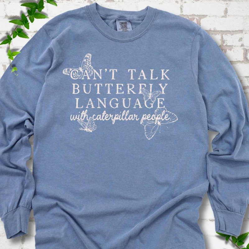 Blue Jean Comfort Colors® long sleeve T-shirt featuring a cream Can't Talk Butterfly Language with Caterpillar People graphic with butterflies