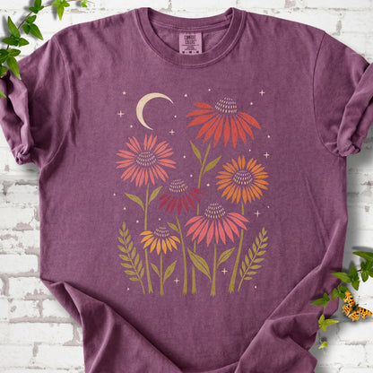 Berry T-shirt laid flat, showing warm-toned coneflowers with green leaves, a cream crescent moon and small stars.